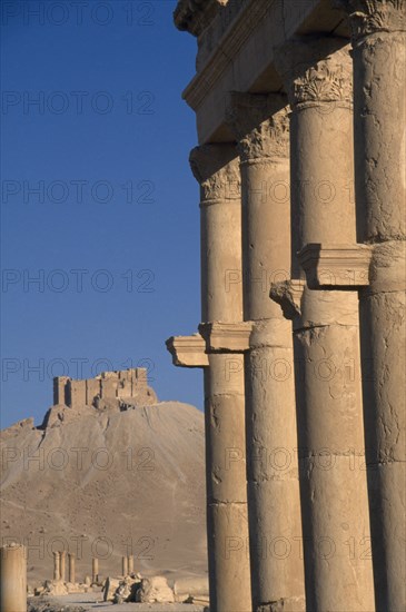 SYRIA, Central, Tadmur, View along colonnaded street with consoles projecting from each column and the Arab Castle or Qalaat Ibn Maan on the hilltop behind.  Palmyra