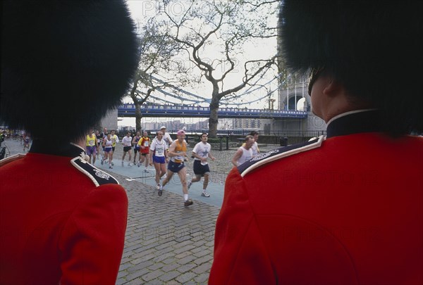 SPORT, Athletics, London Marathon, Runners and Tower Bridge seen between two Guardsmen both wearing a Busby and red tunic Bearskin