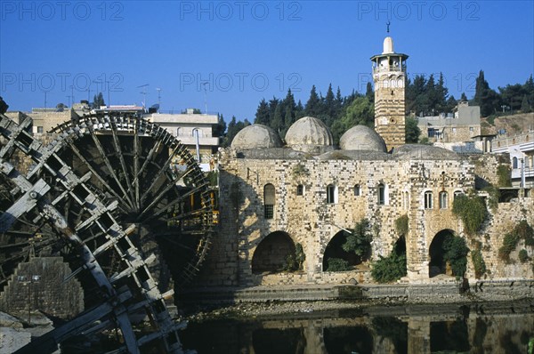 SYRIA, Central, Hama, Wooden norias or waterwheels on the Orontes river and the Al Nuri Mosque dating from 1172 and built of limestone and basalt. Section of wheel in the immediate foreground.