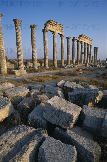 SYRIA, Central, Apamea, Historical site of Roman military headquarters above the village of Qalaat Mudiq.  Colonnaded street with fallen masonry in the immediate foreground.