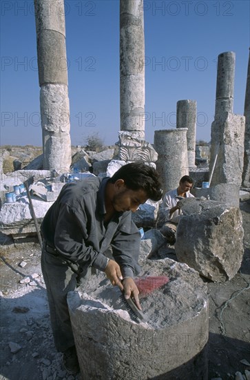 SYRIA, Central, Apamea, Historical site of Roman military headquarters above the village of Qalaat Mudiq.  Restoration workers with columns and fallen masonry behind.