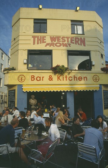 ENGLAND, East Sussex , Brighton, City bar and restaurant with open front and people sitting at crowded outside tables.