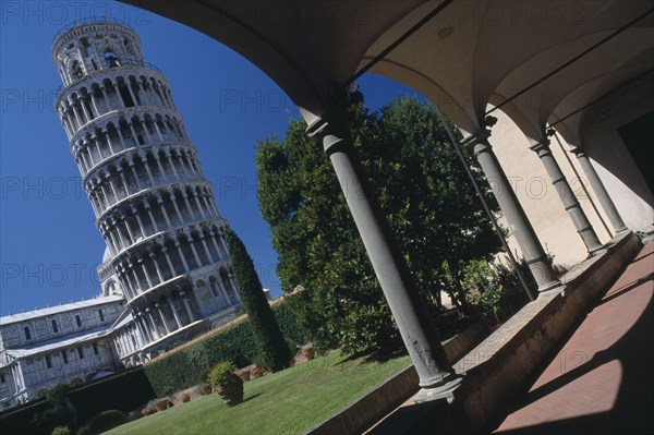 ITALY, Tuscany, Pisa, "Angled view of the Leaning Tower, viewed from the grounds of the Museo del Duomo.  Framed by arch in colonnaded arcade in the foreground. "