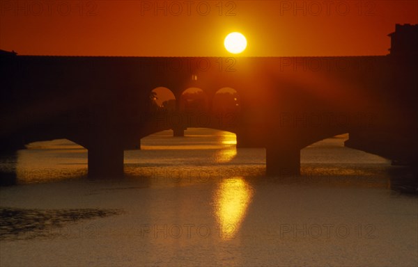 ITALY, Veneto, Florence, Bridge silhouetted against deep red and orange sunset sky seen from Piazzale Michelangelo.