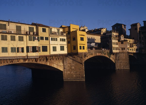 ITALY, Tuscany, Florence, "Ponte Vecchio, the west side in warm, golden light with people standing on central section.  "
