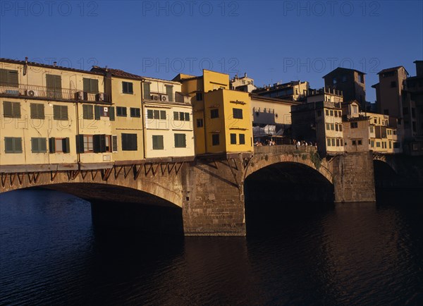 ITALY, Tuscany, Florence, "Ponte Vecchio, the west side in warm, golden light with people standing on central section. "