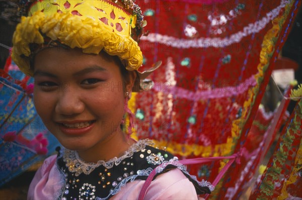 THAILAND, Chiang Mai, "Girl dancer at hill tribe event in yellow, pink and red costume.  Head and shoulders shot. "