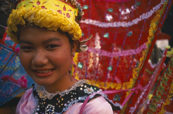 THAILAND, Chiang Mai, "Girl dancer at hill tribe event in yellow, pink and red costume. Head and shoulders shot. "