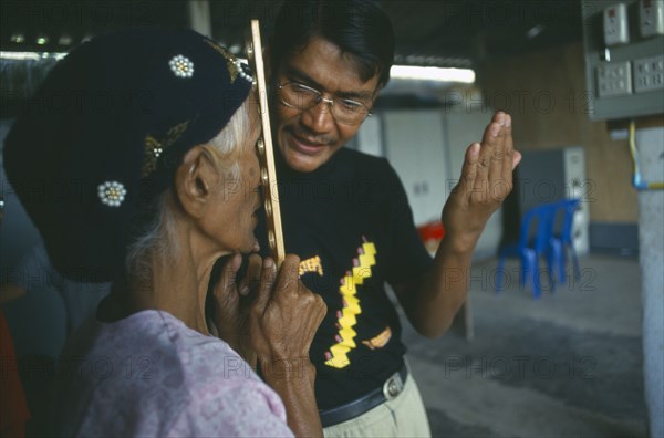 THAILAND, Tak Province, Mae Sot, Male optician giving an elderly woman an eye test at the Mae Tao Clinic.