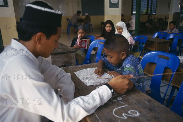 THAILAND, Chiang Mai, "Children studying the Koran at Chiang Mai Mosque under the supervision of a young, male teacher."