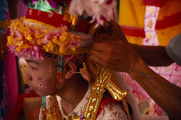 THAILAND, Chiang Mai, Novice monk at ordination ceremony at Wat Chiang Yuen having ornate head dress adjusted.