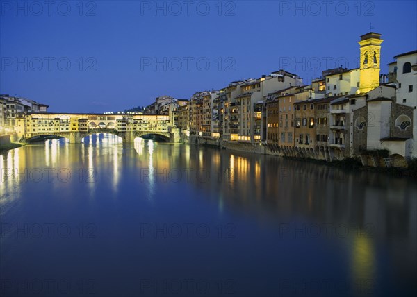 ITALY, Tuscany, Florence, View towards the Ponte Vecchio and waterside buildings at night with lights reflected in the River Arno.