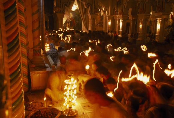 INDIA, Utter Pradesh, Vrindaven, "Dirwali festival, crowds of worshippers holding candles with light trails in dark temple interior.  "