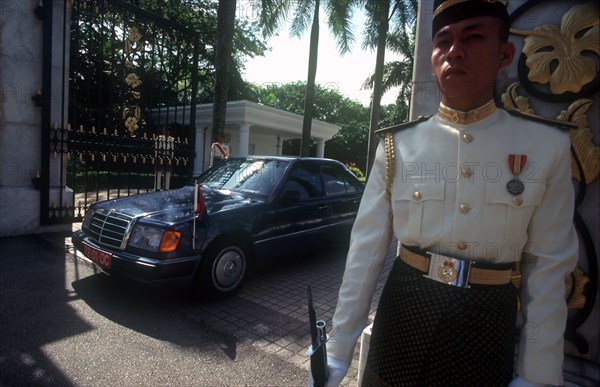 MALAYSIA, Kuala Lumpur, The Kings Palace.  Guard in uniform outside palace gates with official car about to drive through.