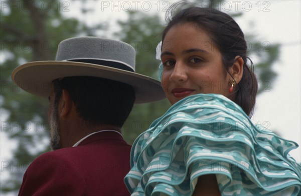 SPAIN, Andalucia, Jerez de la Frontera, Close shot of couple in traditional dress at Jerez Horse Fair with the woman turned towards the camera.