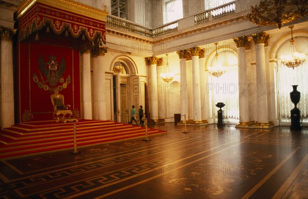 RUSSIA, St. Petersburg, "Winter Palace of the Hermitage, Hall of St. George.  Interior with throne on red dais with decorated canopy, lined by supporting columns and lights reflected in floor surface. "