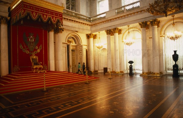 RUSSIA, St. Petersburg, "Winter Palace of the Hermitage, Hall of St. George. Interior with throne on red dais with decorated canopy, lined by supporting columns and lights reflected in floor surface. "