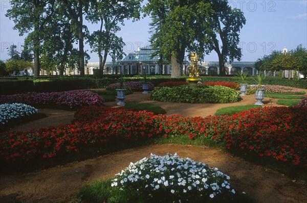 RUSSIA, St. Petersburg, Peterhof Palace grounds.  View over formal gardens and borders with red and white flowers.