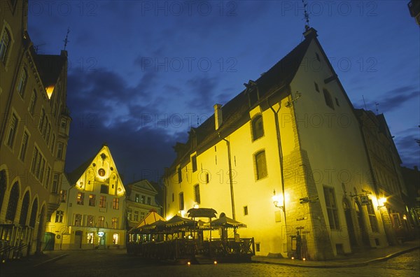 ESTONIA, Tallinn, Exterior of cafe with tables and chairs on cobbled street outside at night.