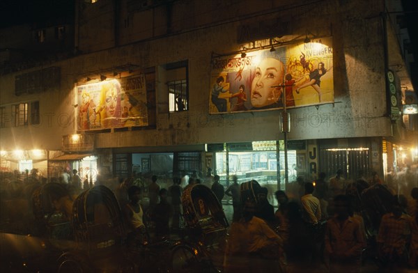 BANGLADESH, Chittagong, "Rickshaw wallahs in front of cinema with posters advertising films above the entrance, illuminated at night."