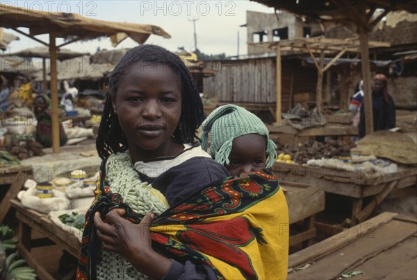 KENYA, Children, Family, Young woman carrying her baby on her back in a colourful sling.