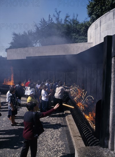 PORTUGAL, Biera Litoral, Fatima, Pilgrims throwing candle offerings into fire