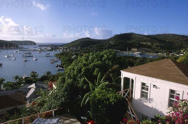WEST INDIES, Antigua, English Harbour, Ordnance Bay.  View over bay with moored yachts and tree covered coastline with part seen white painted house in the foreground.