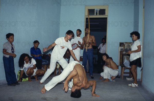 20018919 BRAZIL  Capoeira Local men in animated poses of martial arts  inside a small room with spectators.