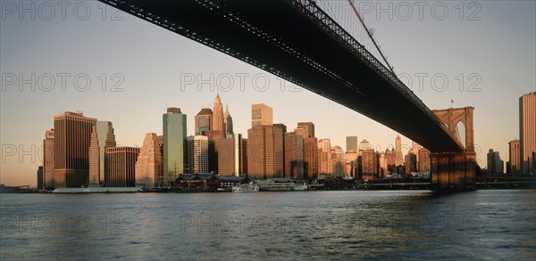 USA, New York State, New York, Lower Manhattan.  Post September 11 skyline from Brooklyn in evening light with underside of Brooklyn         Bridge in the foreground.