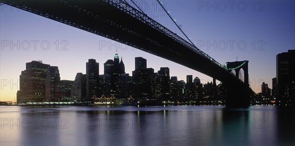 USA, New York State, New York, Lower Manhattan.  Post September 11 skyline from Brooklyn illuminated at night with Brooklyn Bridge in the foreground.