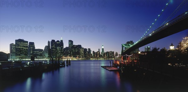 USA, New York State, New York, Lower Manhattan.  Post September 11 skyline from Brooklyn illuminated at night with Brooklyn Bridge in the foreground.