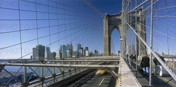 USA, New York State, New York, Lower Manhattan.  Post September 11 skyline from Brooklyn Bridge intersected by tension wires with traffic and pedestrians crossing.