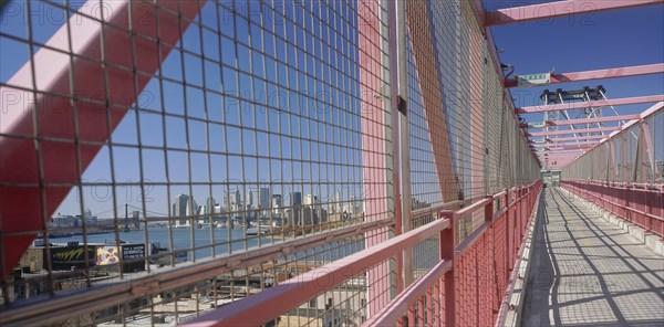 USA, New York State, New York, Williamsburg Bridge.  View along footbridge lined by high sided metal barriers towards city skyline.