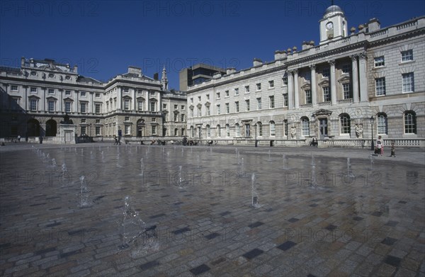 ENGLAND, London, Somerset House and courtyard with rows of small fountains spouting from the ground with onlookers and visitors in the distance.