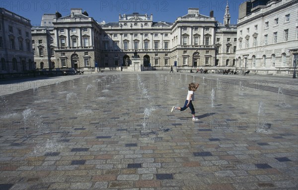 ENGLAND, London, Somerset House and courtyard with rows of small fountains spouting from the ground with a girl running between them.