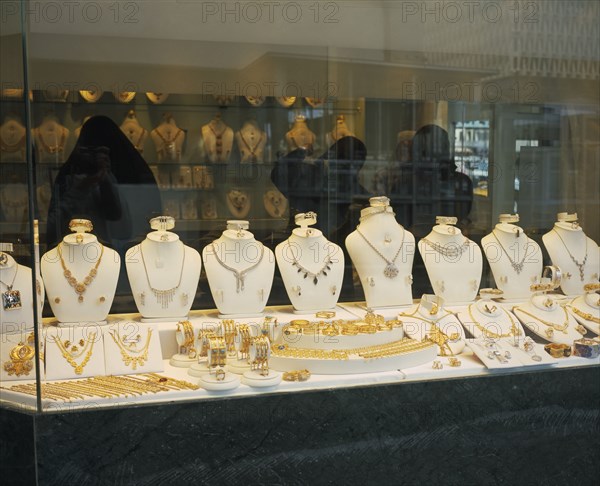 KUWAIT, Kuwait City , "Gold Souq.  Three women in black Burqa inside jewellery shop, seen through window with display  of gold and silver."