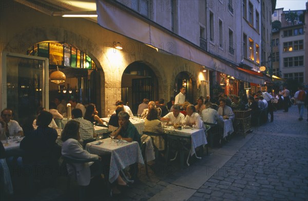 FRANCE, Rhone Loire, Rhone, Lyon.  People eating at outside tables in street side restaurants in evening.