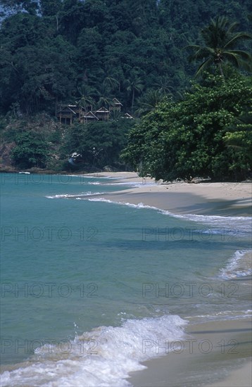 THAILAND, Trat Province, Koh Chang, Chalets on a hillside at the northern end of Aow Bai Lan Lonely Beach with surf rolling onto the beach
