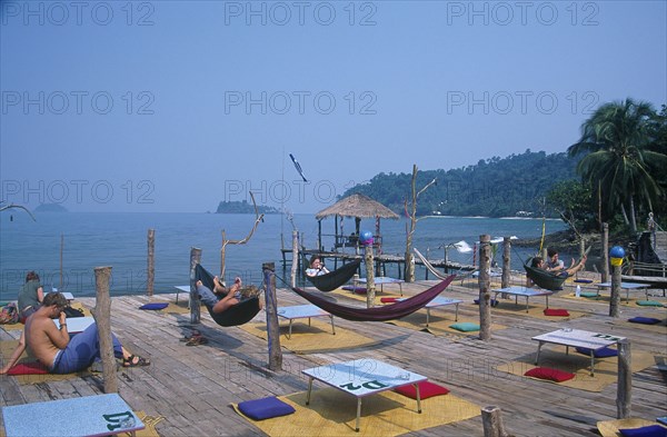 THAILAND, Trat Province, Koh Chang, People lying in hammocks on a wooden platform built over rocks on Aow Bai Lan Lonely Beach