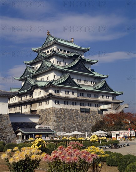 JAPAN, Honshu, Nagoya, The Castle with floral gardens in the foreground and small cabin with tables and chairs outside.