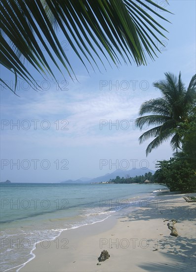 THAILAND, Trat Province, Koh Chang, Kai Bae Beach view along the coast framed by palm leaves.