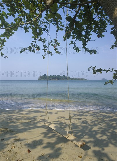 THAILAND, Trat Province, Koh Chang, Kai Bae Beach view from sandy beach out towards Koh Man Nai Island with wooden swing in the foreground hanging from trees overhead.
