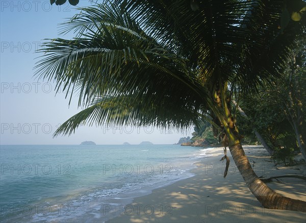 THAILAND, Trat Province, Koh Chang, "Lonley Beach, Aow Bai Lan. View along the sandy bay with over hanging tree and small islands in the distance."