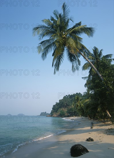 THAILAND, Trat Province, Koh Chang, "Lonley Beach, Aow Bai Lan. View along the sandy bay with overhanging palm tree and small islands in the distance."