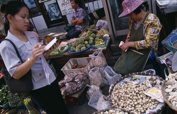 THAILAND, North, Chiang Mai, Wholesale Food Market.  Female buyer for restaurant purchasing mushrooms from vendor.