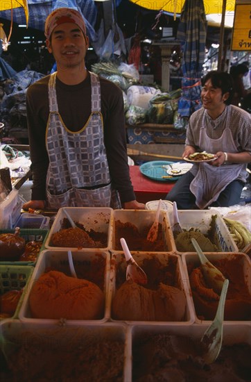 THAILAND, North, Chiang Mai, Wholesale Food Market.  Male vendor behind stall selling  selection of curry pastes displayed in plastic bowls.