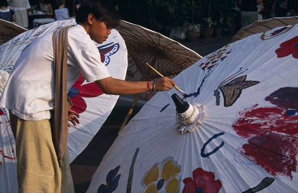 THAILAND, North, Chiang Mai, Tha Phae Road.  Young man taking part in umbrella painting competition on a sunday when the road is closed to traffic.