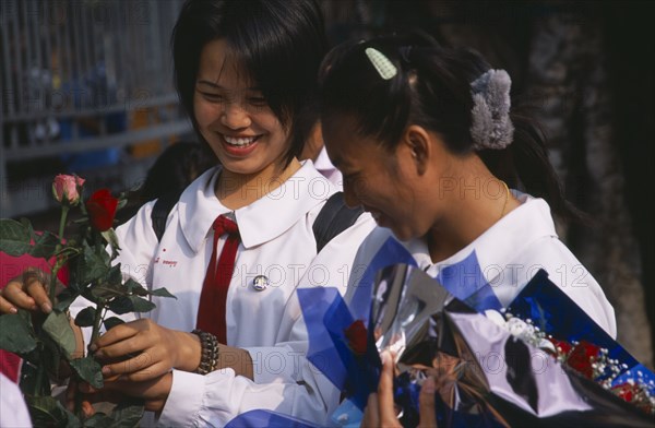 THAILAND, North, Chiang Mai, Phra Pokklao.  St Valentines day with two Thai school girls in uniform buying roses from outside High School.