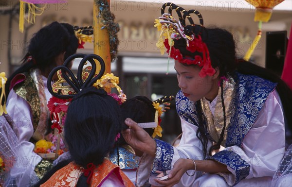 THAILAND, North, Chiang Mai, "Chinese New Year.  Young woman applying make-up to another, both in costume with elaborate hair styles."
