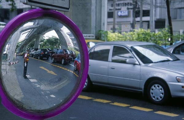 THAILAND, Bangkok, Transport, Roadside mirror reflecting traffic policeman with passing traffic.